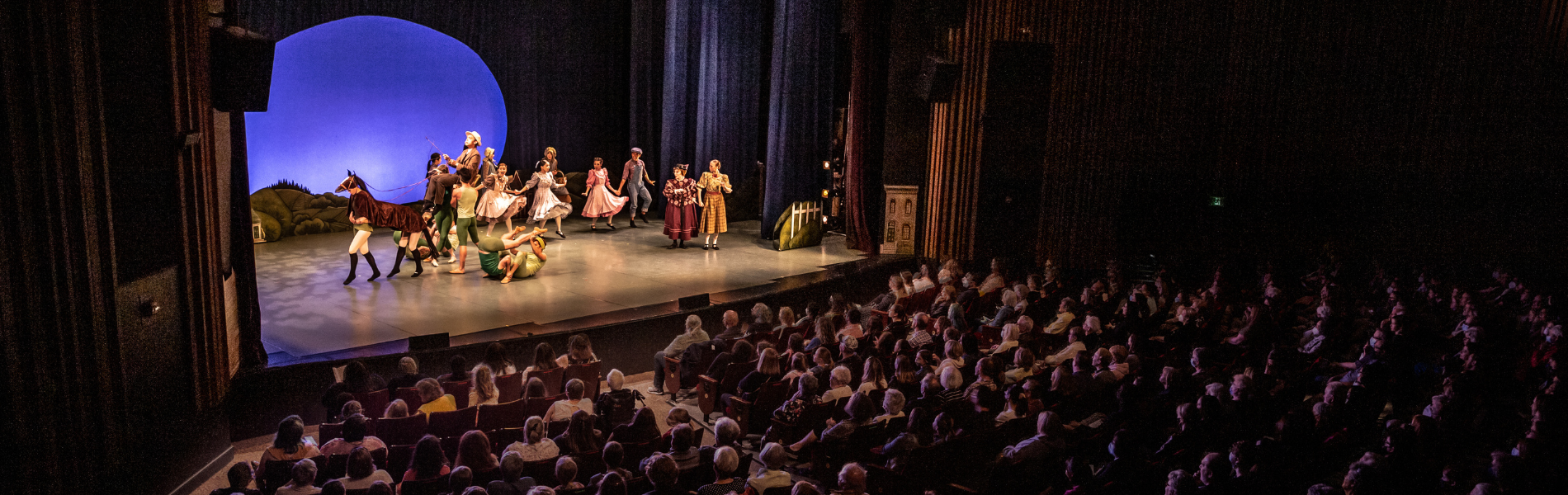 A full audience watching a dance production on the Playhouse stage