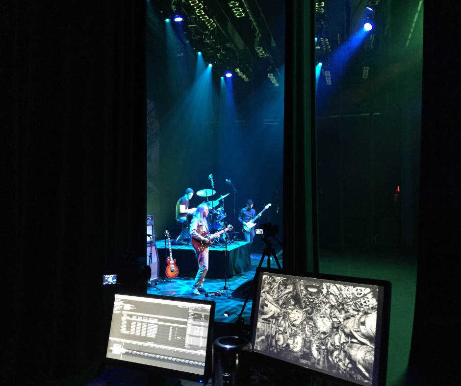 A band performs on stage, view from sidestage