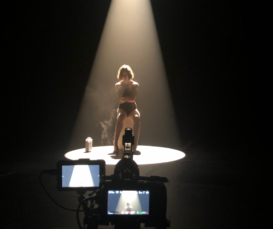 Sydney Hallett in the spotlight on a dark stage