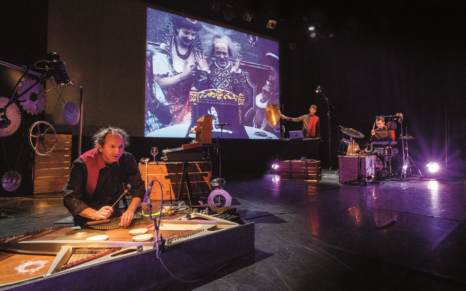 A man on stage playing an instrument machine with a projection behind him