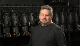 Jeff Fevens in a black tshirt in front of a back stage background