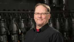 Jonathon Harpur in a black shirt against a black stage backdrop.