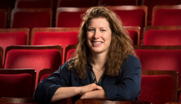 Meghan Callaghan in a blue shirt against a background of red theatre seats