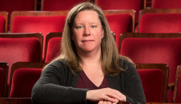 Sally Goodwin facing the camera against a backdrop of red theatre seats.
