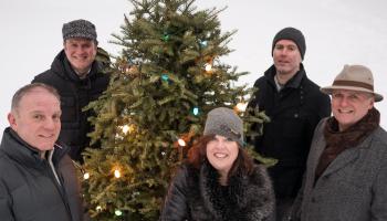 Barra MacNeils standing around a Christmas tree.