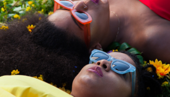 Two women of OKAN laying in the grass on their backs