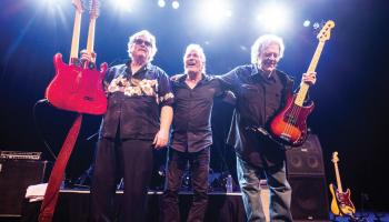 The Stampeders standing on stage holding up guitars.