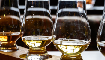 a row of whiskey glasses with different whiskeys in each