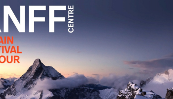 A photo of snowy mountain tops with the sun setting behind them.