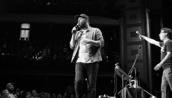 Black & white photo of two members of Choir! Choir! Choir! on stage at a large theatre
