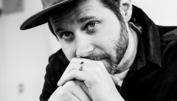 Black & white image closely cropped of Dan Mangan with his hands in front of his chin