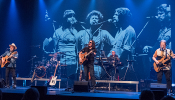 Musicians playing instruments on the stage with projection behind them.