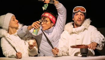 Three actors dressed as researchers in white parkas against a black background