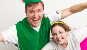 An actor dressed as Peter Pan with an actor dressed as Tinkerbell, both with their arms outstretched