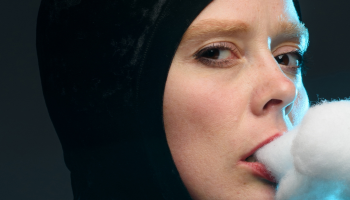 Close up of Ingrid Hansen looking sideways at the camera with cotton fluff coming out her mouth to look like smoke