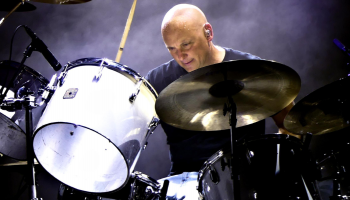 Martin Levac sitting at a bright white drum kit against a dark background