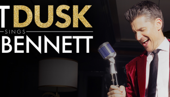 Matt Dusk in a red velvet jacket singing into an old fashioned microphone with the text "Matt Dusk sings Tony Bennett"