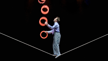Performer Jamie Adkins on a tightwire rope, juggling multiple rings