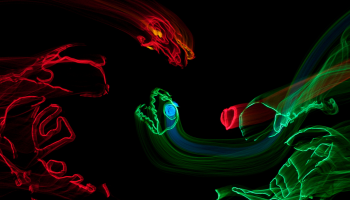 Red and green lights being used against a black backdrop to make the shapes of dinosaurs