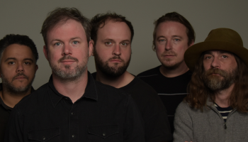 A close up of the five members of Wintersleep standing together looking right at the camera