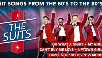 Four people in red suits singing into microphones over a blue and red background. The words 'Hits songs from the 50's to the 80's, The Suits' in white lettering.