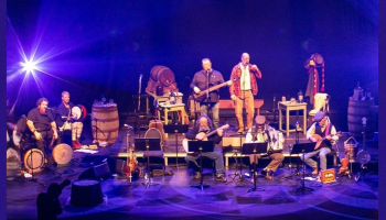 An image of musicians on stage with purple and blue lighting.