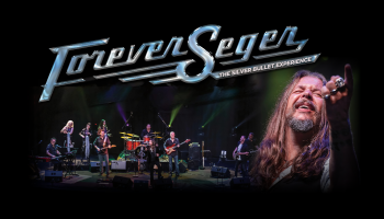 The words, 'Forever Seger The Silver Bullet Experience' in silver lettering above a band on stage and the tribute artist pointing into the distance. 