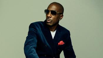 JB Smoove sits, suited.
