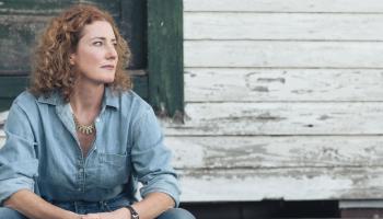 Kathleen Edwards sits outside of an old home looking wistfully off camera