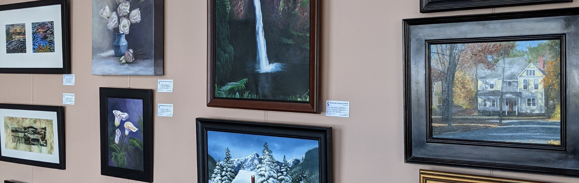 A display wall of multiple art works hanging at the Playhouse