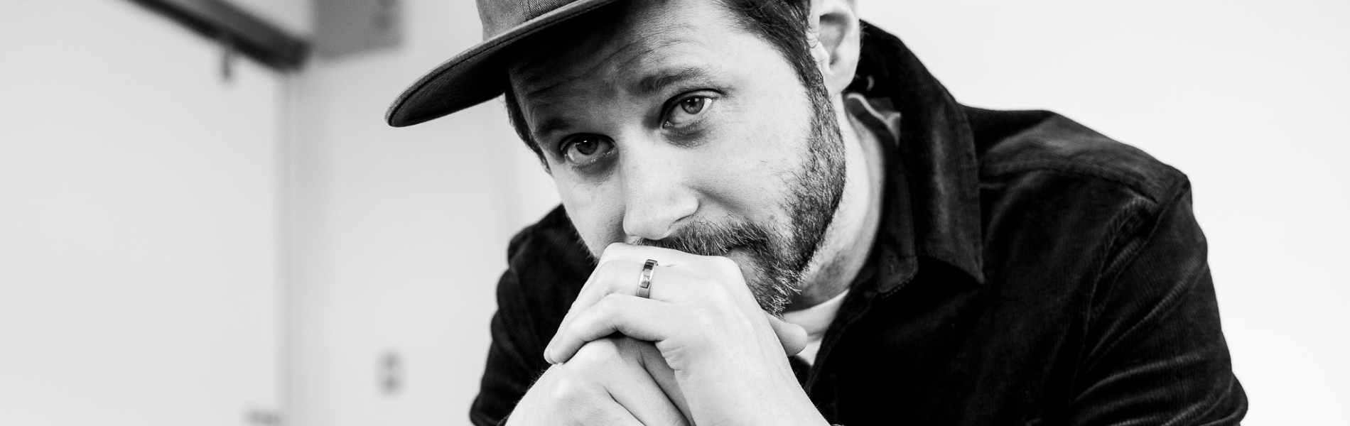 Black & white image closely cropped of Dan Mangan with his hands in front of his chin