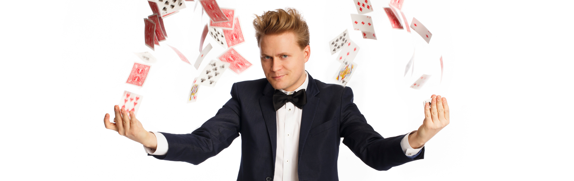 A magician with his arms extended, cards flying in an arc from his hands