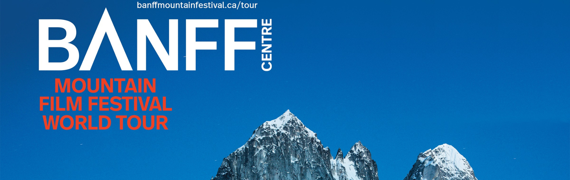 Blue sky and mountain tops with the words BANFF Centre Mountain Film Festival on the left or the mountain tops.