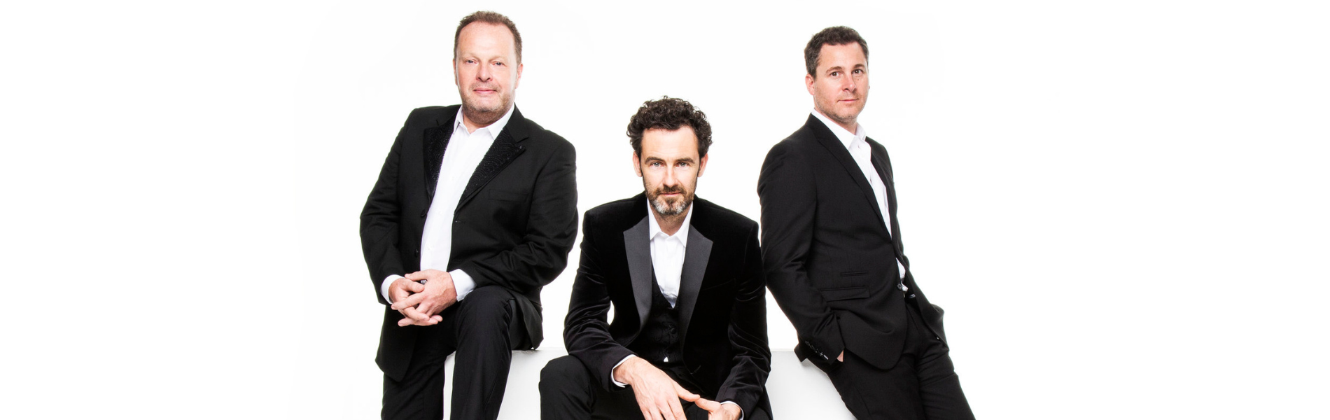 3 members of The Celtic Tenors in black suits against a white background