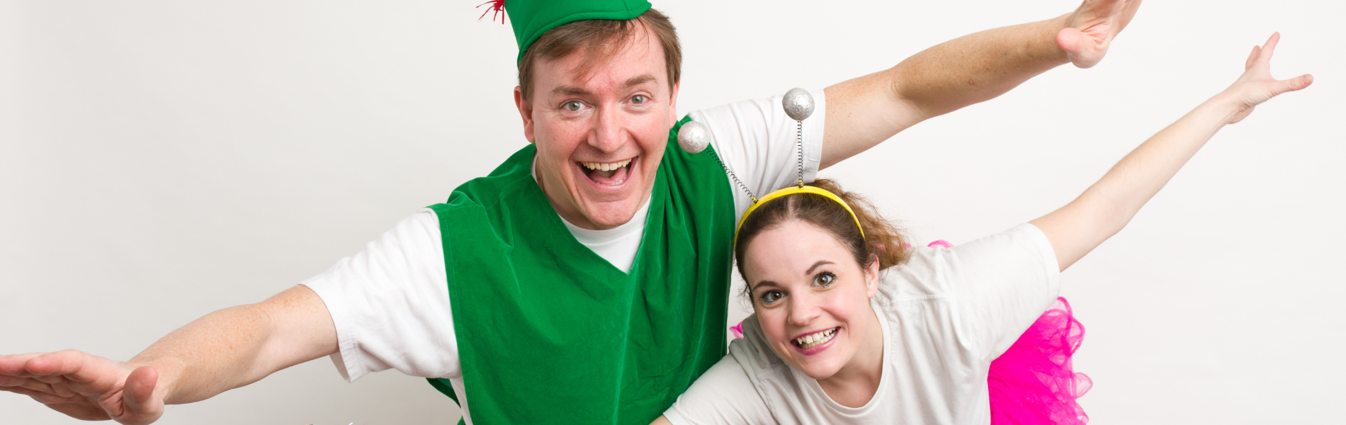 An actor dressed as Peter Pan with an actor dressed as Tinkerbell, both with their arms outstretched