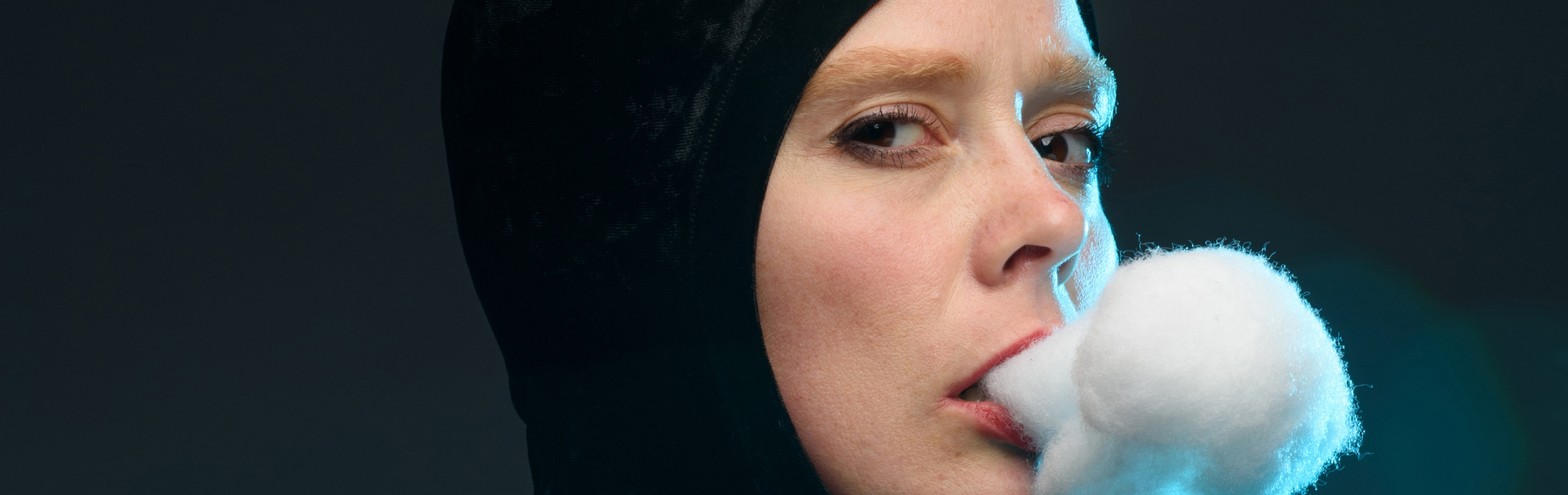 Close up of Ingrid Hansen looking sideways at the camera with cotton fluff coming out her mouth to look like smoke