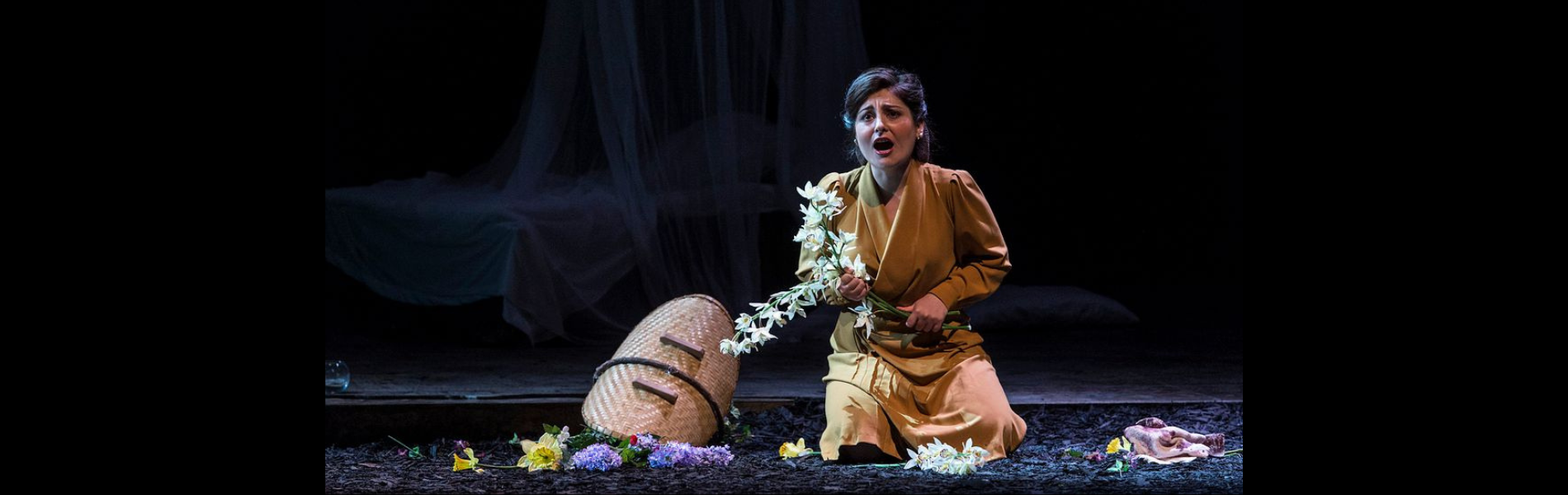 A person on stage with a basket and flowers. 