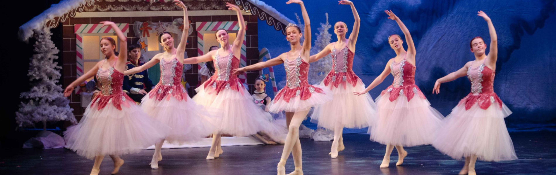 Ballerinas dancing on stage with The Nutcracker set in the background.