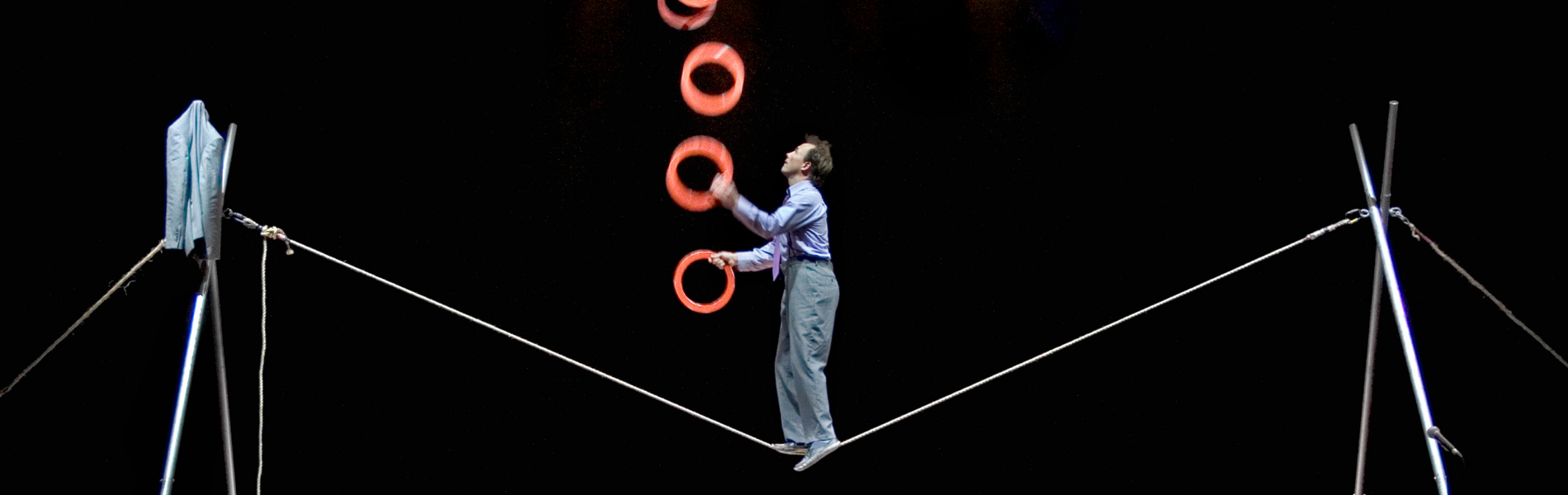 Performer Jamie Adkins on a tightwire rope, juggling multiple rings