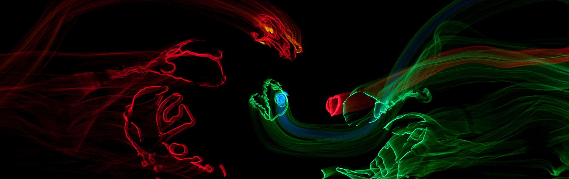 Red and green lights being used against a black backdrop to make the shapes of dinosaurs