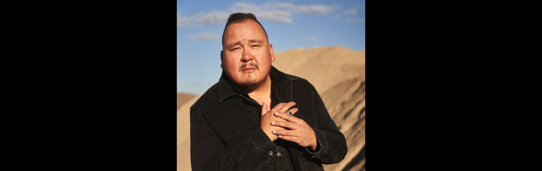 A portrait of William Prince standing in front of a mountain.
