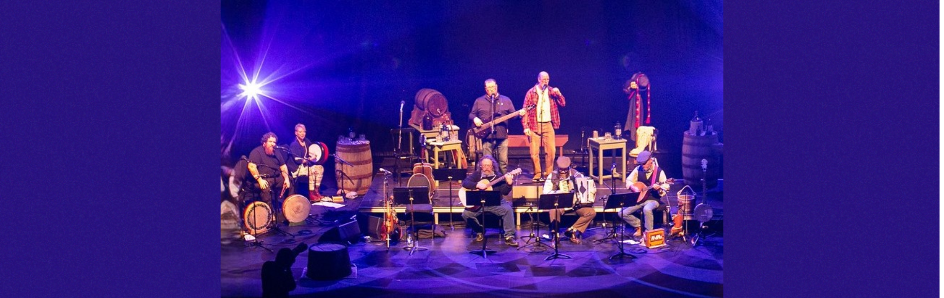 An image of musicians on stage with purple and blue lighting.